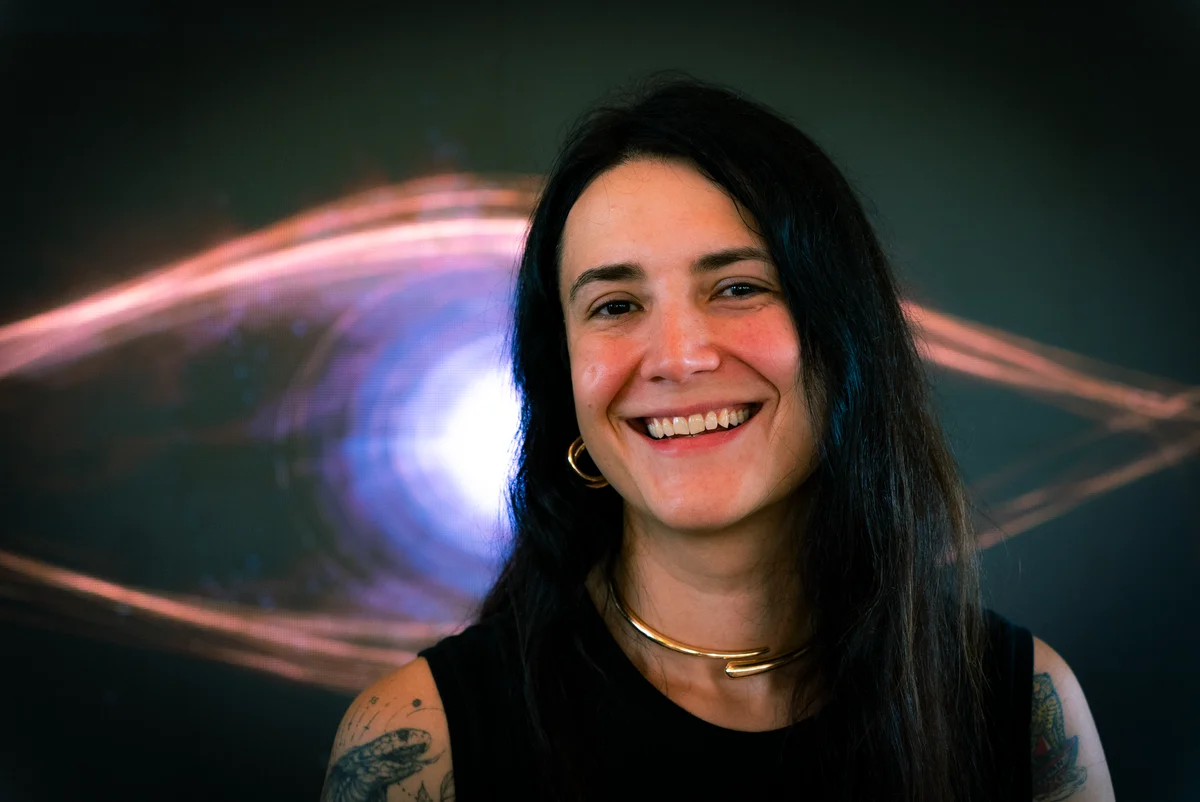 Alma sorrindo, com a projeção de Lume ao fundo